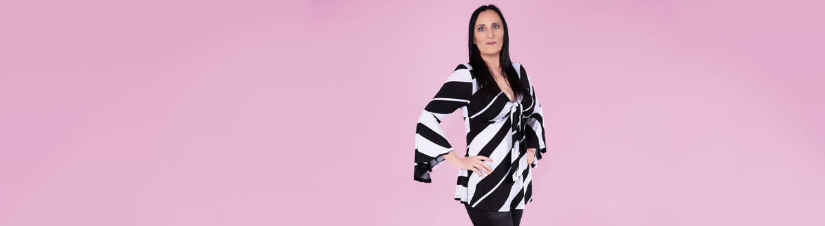 Monika (52) nach ihrer Gewichtsabnahme mit Precon in schwarz-weißer Bluse vor rosa Hintergrund