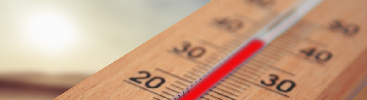 Nahaufnahme eines Holzthermometers mit über 30 Grad vor sonnigem Himmel