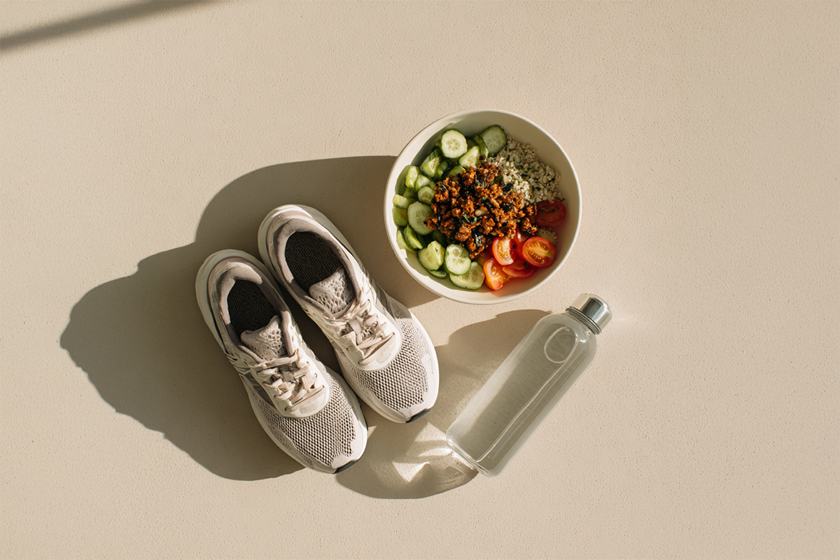 Sportschuhe, Trinkflasche und Gemüse-Bowl von oben auf hellem Untergrund – Abnehmen mit Sport und Ernährung