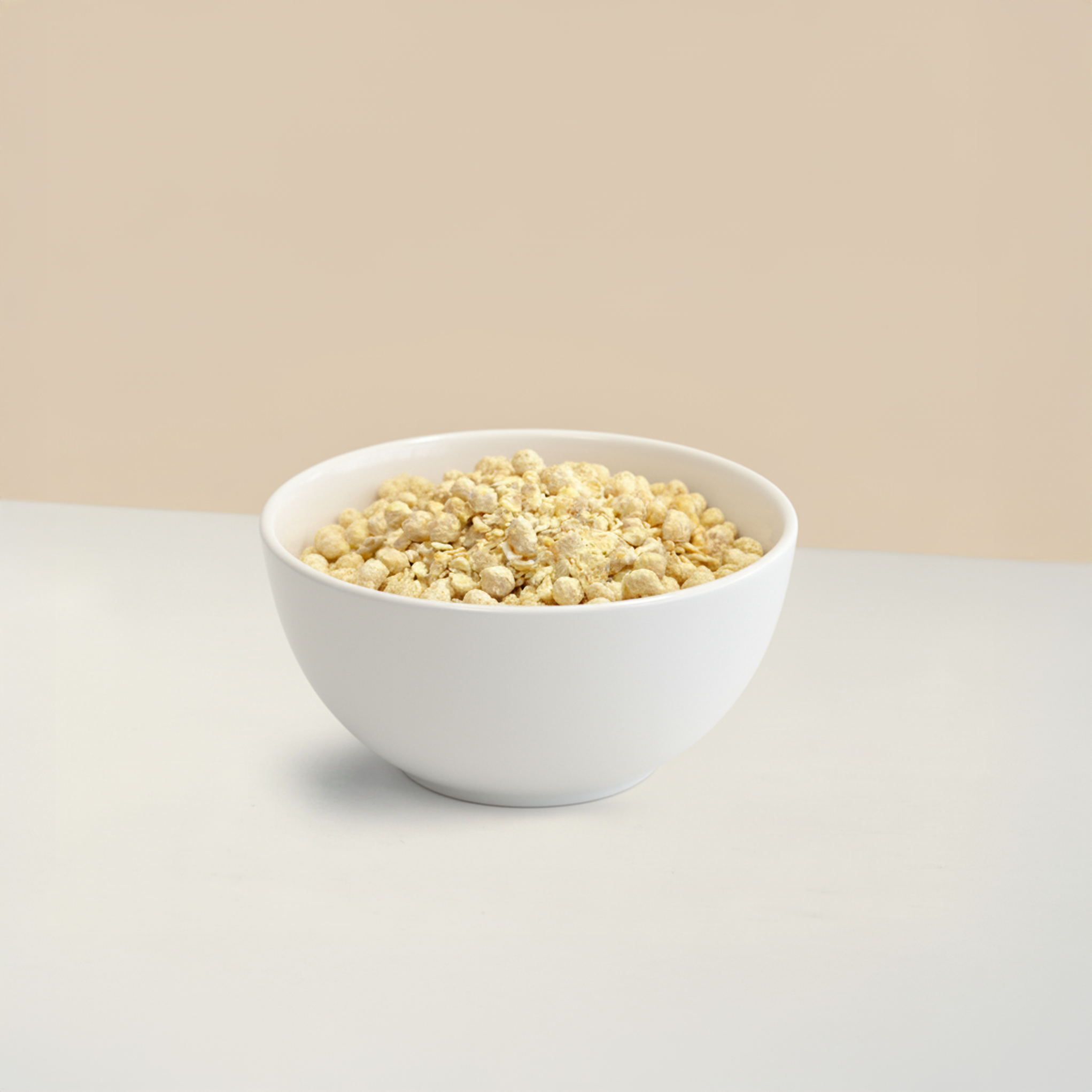 Eine dunkle Keramikschale, gefüllt mit Precon Tropical Mango Müsli, steht auf einer weißen Fläche vor einem beigen Hintergrund.