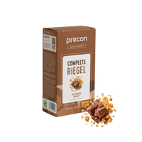 Auf der Vorderseite einer aufrecht stehenden braunen Verpackung der „Complete Riegel Schoko Crisp“-Riegel der Firma Anona GmbH ist ein Bild von Schokoladenstückchen und knusprigem Müsli zu sehen.